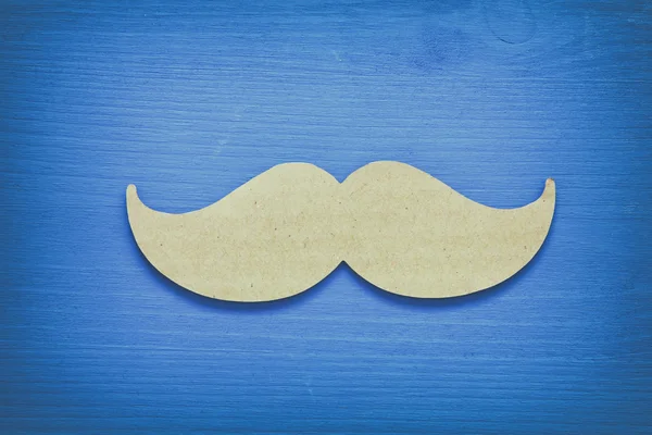 Fond en bois bleu et moustache en papier — Photo