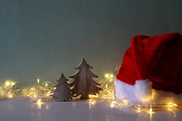 Albero di Natale con ghirlanda luci accanto al cappello di Babbo Natale — Foto Stock