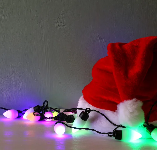 Luci ghirlanda colorate accanto al cappello di Babbo Natale — Foto Stock