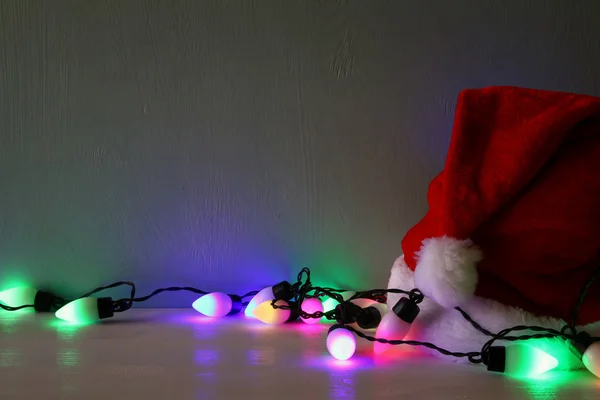 Luci ghirlanda colorate accanto al cappello di Babbo Natale — Foto Stock
