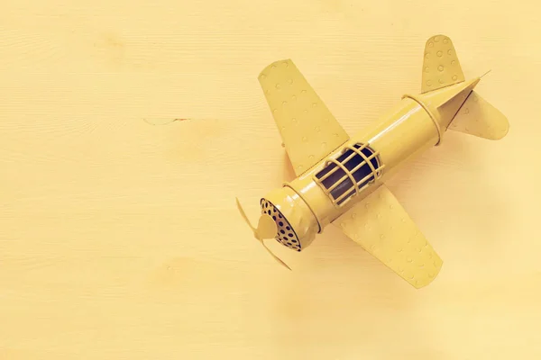 木製のテーブルの上にレトロな黄色い金属製のおもちゃの飛行機のイメージ — ストック写真