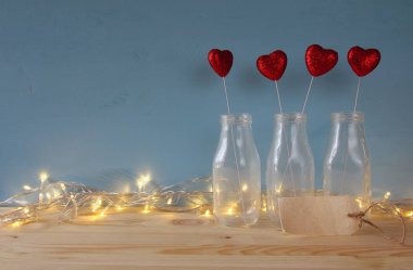 Ahşap masa üzerinde cam vazo içinde Glitter Kalpler