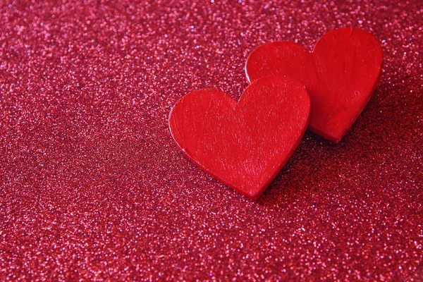 Ξύλινα κόκκινες καρδιές σε κόκκινο γυαλιστερό φόντο — Φωτογραφία Αρχείου