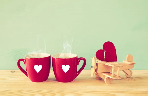 Houten vliegtuig met hart naast paar koffie kopjes — Stockfoto