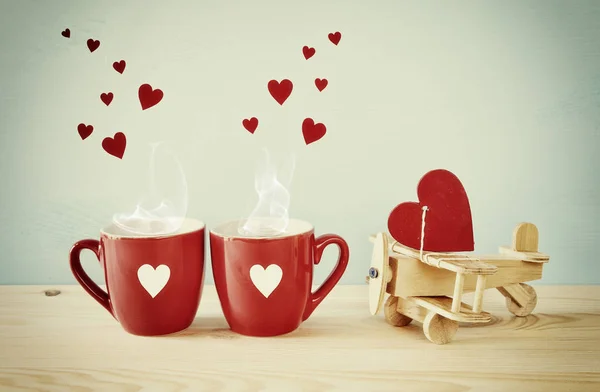 Plano de madeira com coração ao lado de dois copos de café — Fotografia de Stock