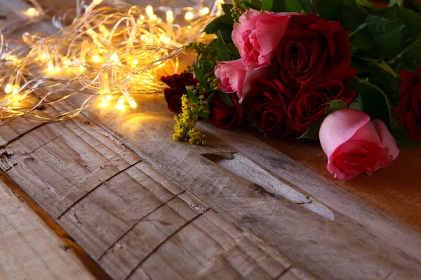Букет роз рядом с золотыми гирляндами — стоковое фото