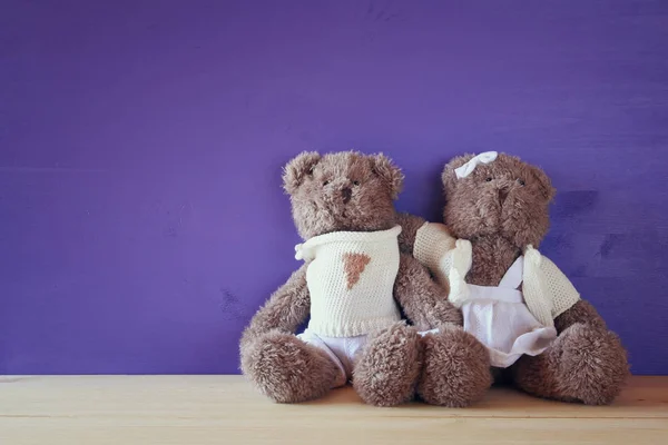 Couple of cute teddy bears hugging on wooden table — Stock Photo, Image