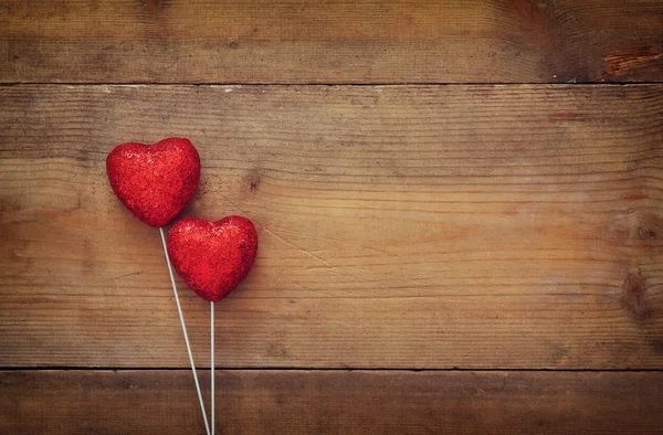 Couple de coeurs de paillettes rouges sur fond bois — Photo