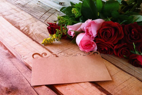 Boeket rozen daarna op de brief op houten tafel — Stockfoto