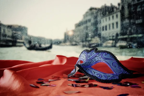 Máscara veneziana em tecido de seda vermelha na frente de Veneza embaçada — Fotografia de Stock