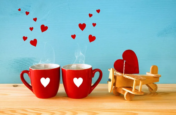 Wooden plane with heart next to couple of coffe cups — Stock Photo, Image