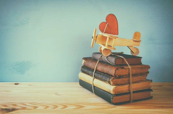 Avion en bois avec cœur sur la pile de vieux livres — Photo