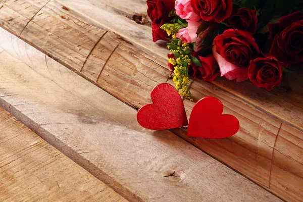 Czerwone serca i róże na drewnianym stole — Zdjęcie stockowe