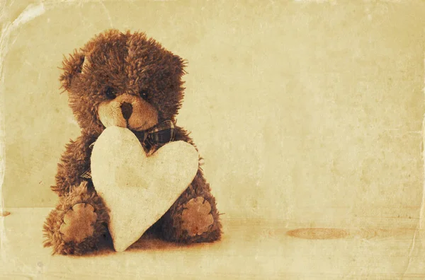 Lindo oso de peluche sentado y sosteniendo un corazón — Foto de Stock