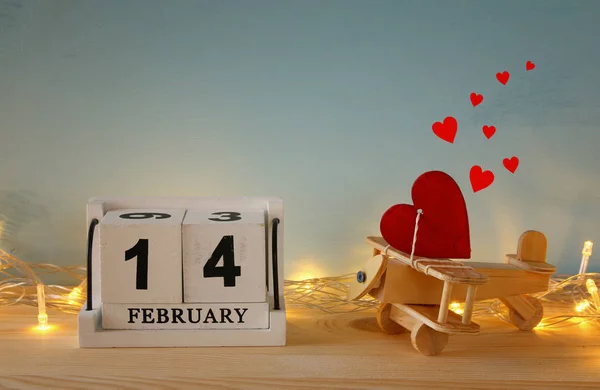 Wooden plane with heart next to calendar — Stock Photo, Image