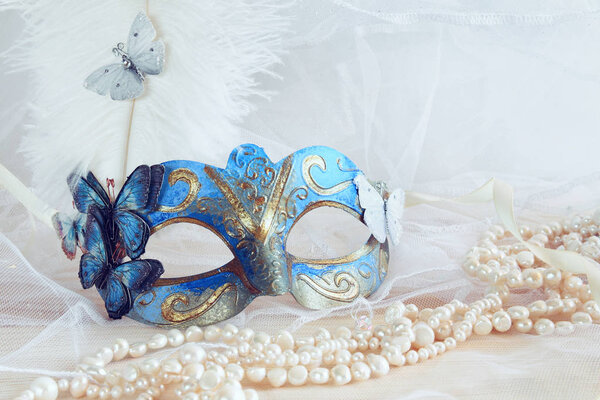 blue venetian mask next to pearls