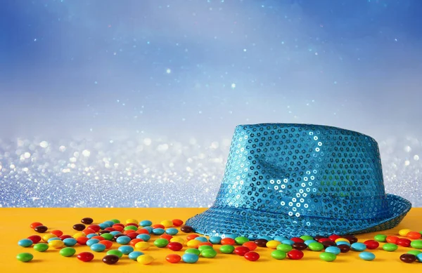 Renkli şekerler yanındaki mavi parlak parti şapka — Stok fotoğraf
