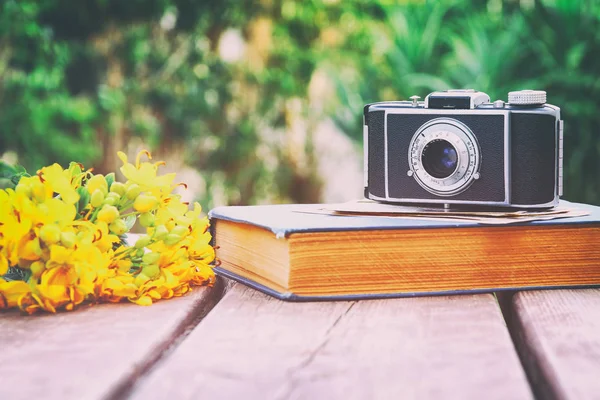 Old book, vintage photo camera next to field flowers — Stock Photo, Image