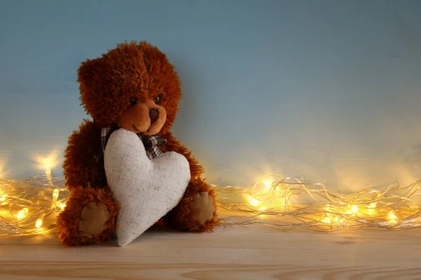 Schattige teddybeer vergadering en het houden van een hart, op houten tafel — Stockfoto