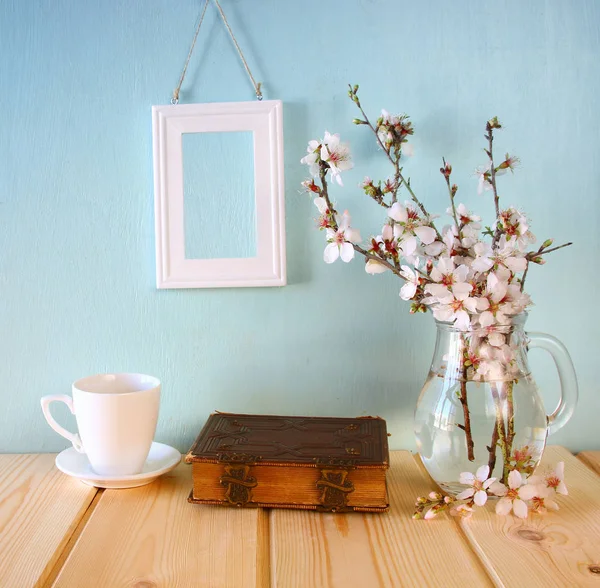 Old book, cup of coffee next to spring white flowers — Stock Photo, Image