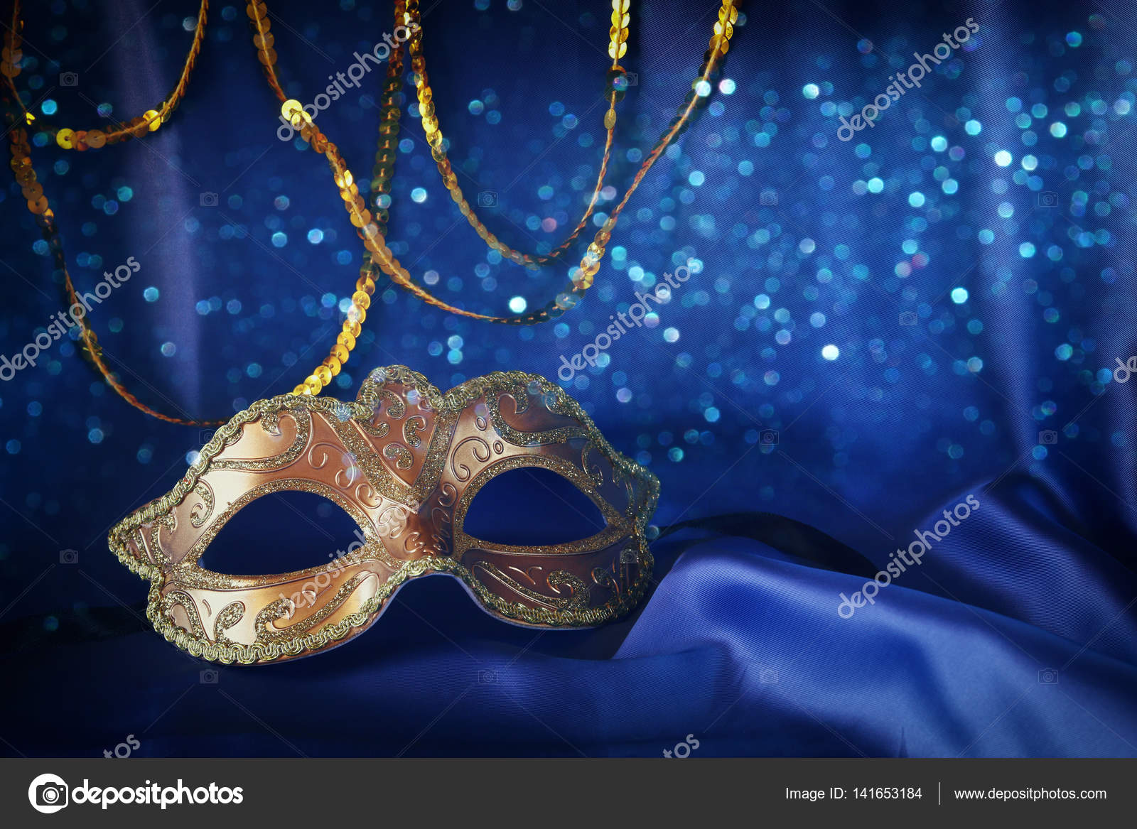 Gold venetian mask on blue silk background Stock Photo by ©tomert 141653184