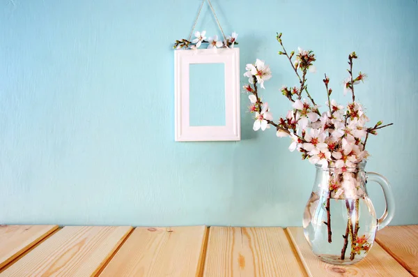 Branches with flowers in glass jug — Stock Photo, Image