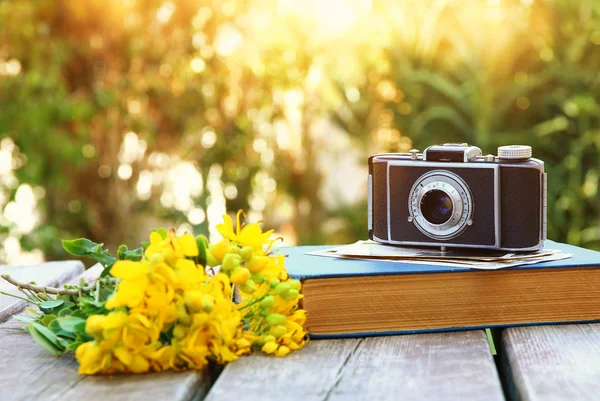 Oud boek, vintage fotocamera naast veld bloemen — Stockfoto