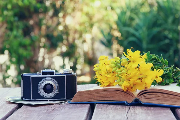 Старая книга, винтажная фотокамера рядом с полевыми цветами — стоковое фото