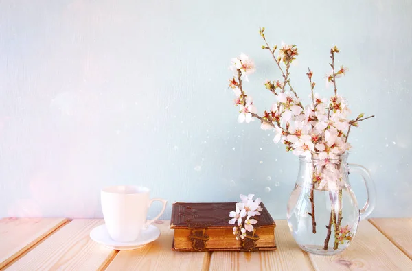 Vieux livre, tasse de café à côté de fleurs blanches de printemps — Photo