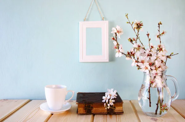 Gammal bok, kopp kaffe bredvid vita vårblommor — Stockfoto