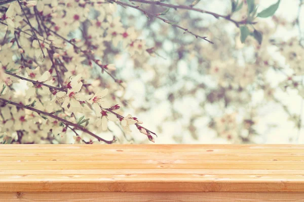 Wooden table in front of spring cherry blossom trees — Stock Photo, Image
