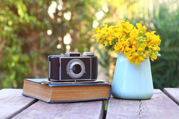 Oud boek, vintage fotocamera naast veld bloemen — Stockfoto