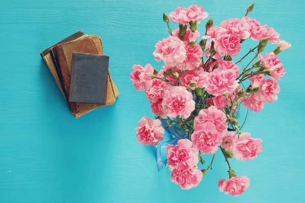 カーネーションの花と古い本の花束 — ストック写真