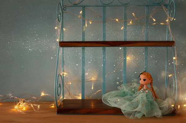 Cute doll next to warm garland lights