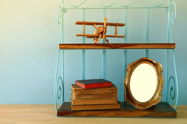 Estante vintage con viejo juguete plano de madera, libros y marco de fotos en blanco — Foto de Stock