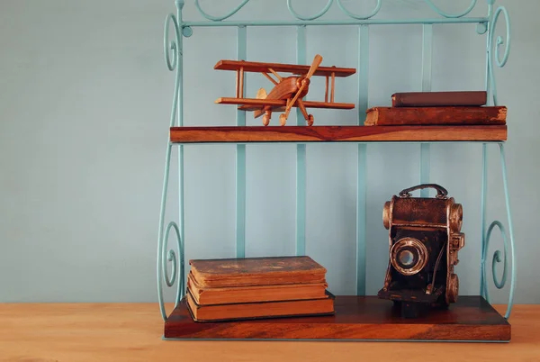 Vintage shelf with old wooden plane toy, books and decorative camera. — Stock Photo, Image