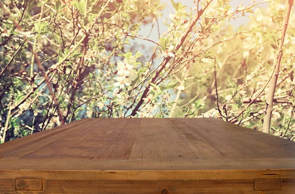 Mesa rústica de madeira na frente do fundo da primavera. imagem filtrada vintage. exposição do produto e conceito do piquenique — Fotografia de Stock