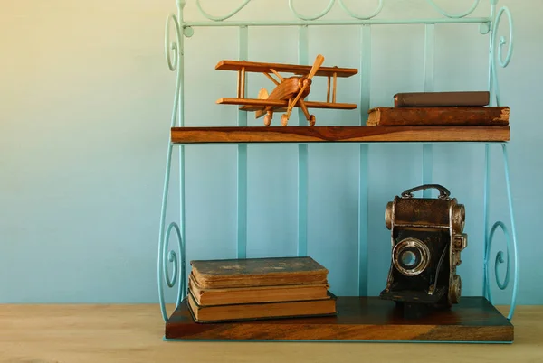 Vintage shelf with old wooden plane toy, books and decorative camera. — Stock Photo, Image
