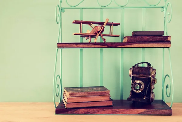 Estante vintage con viejo juguete plano de madera, libros y cámara decorativa . —  Fotos de Stock