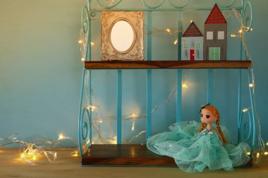 Sevimli bebek, boş fotoğraf çerçevesi ve sıcak garland ışıklar yanındaki küçük ahşap evler