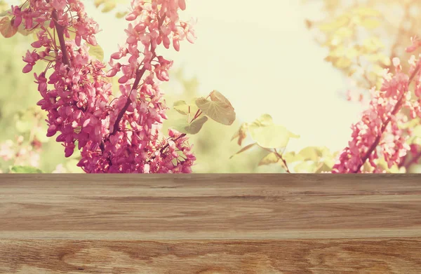 Wooden table in front of spring white cherry blossoms tree — Stock Photo, Image