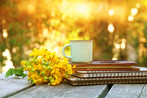 Notebooki, obok pola kwiatów na drewnianym stole na świeżym powietrzu — Zdjęcie stockowe