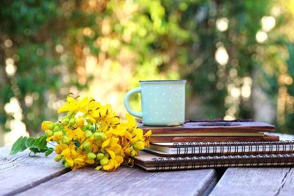 Poznámkové bloky vedle pole květin na dřevěný stůl venku — Stock fotografie
