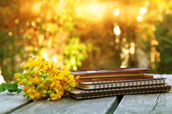 Notizbücher neben Feldblumen auf Holztisch im Freien — Stockfoto