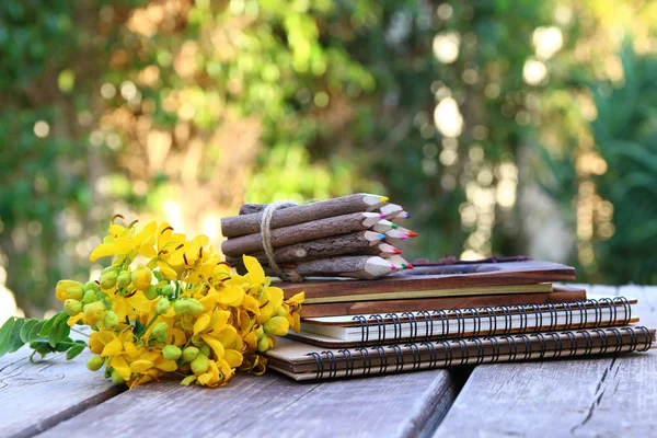 Cuadernos, lápices de colores en la mesa de madera al aire libre — Foto de Stock