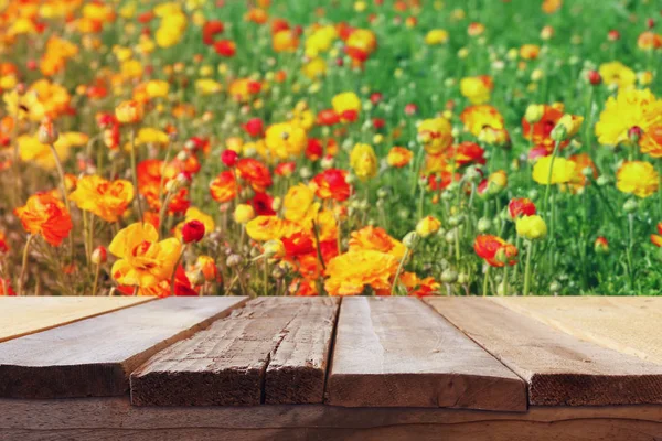 Träskiva bordet framför sommaren blommor fält. — Stockfoto