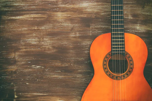 Close up of acoustic guitar against a wooden background — Stock Photo, Image