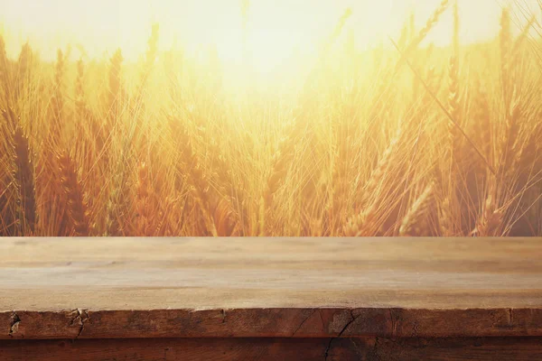 Dřevěné desce stole pole pšenice na slunce světlo — Stock fotografie