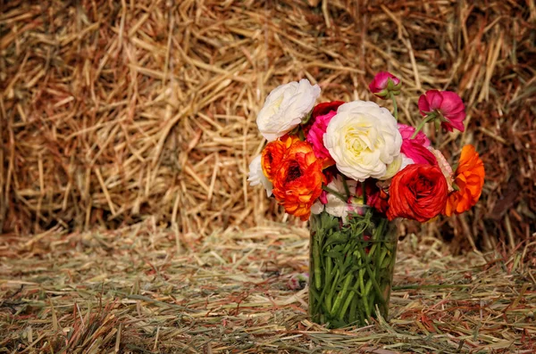 Beautiful spring bouquet of flowers on dry wheat haystack — Stock Photo, Image