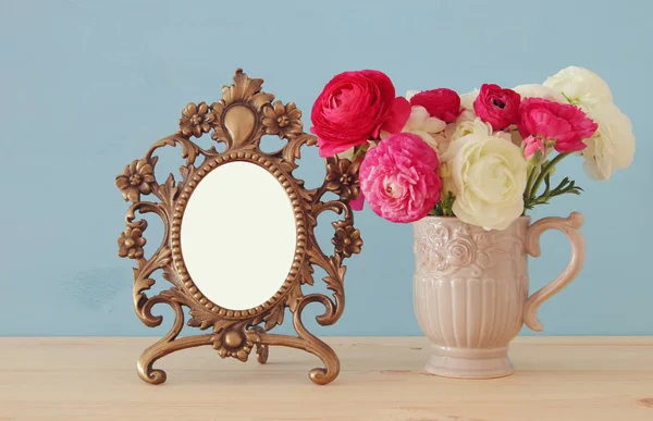 Buquê de flores da primavera ao lado de moldura de foto vintage em branco — Fotografia de Stock